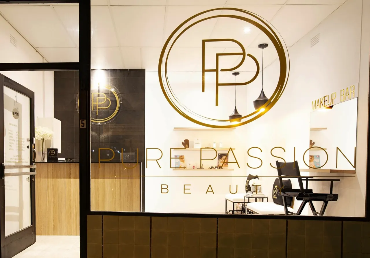 Inside Pure Passion Beauty through the shop window: the gold PP monogram on a white wall, black tiled reception and makeup bar