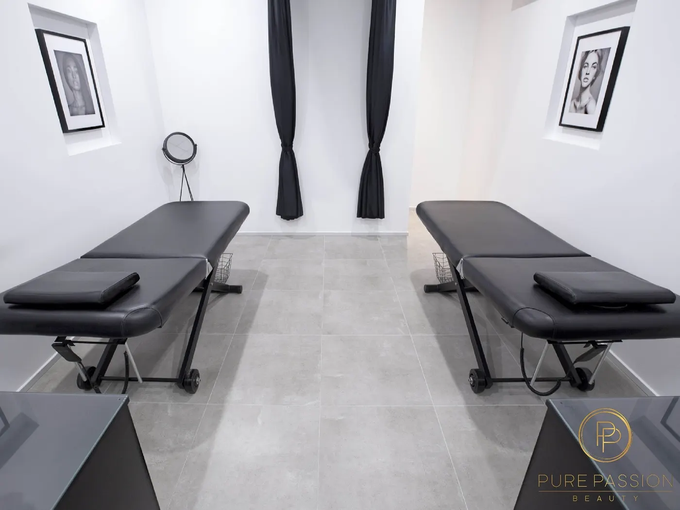 Two black treatment beds in the white treatment room